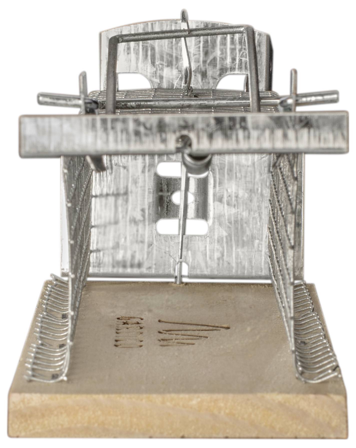 Metal mousetrap on a wooden board. The trap is set and ready for use.
