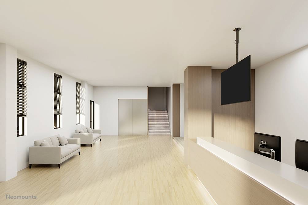 Modern office reception area with light wooden flooring, a minimalist reception desk, and a black screen mounted on the ceiling.