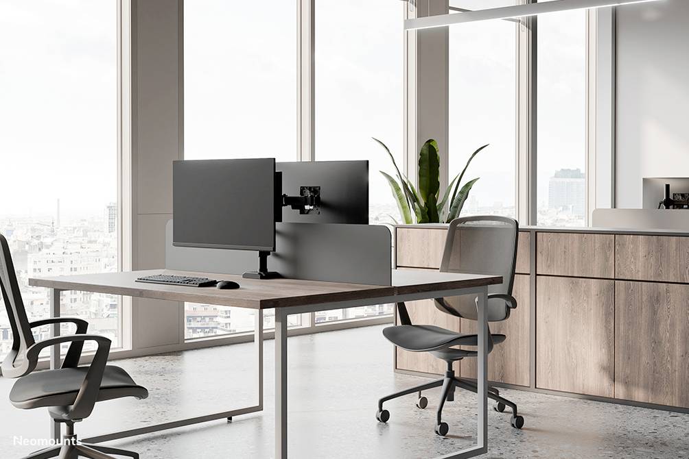 Modern office environment with two office chairs and a desk featuring a dual-monitor setup. Window in the background with a city view.