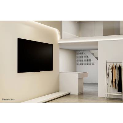 A modern, minimalist room with a large wall-mounted television, a wardrobe, and understated lighting.