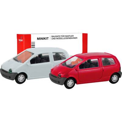 A red and a white model car in front of packaging with the inscription 'MINIKIT Construction Kit for Hobbyists and Model Railway Enthusiasts'.