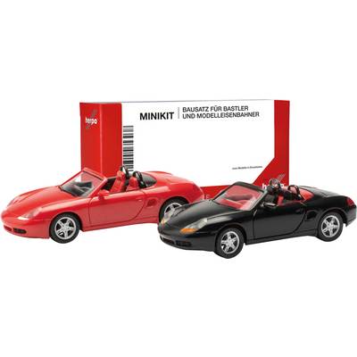 Two model cars, one red and one black, in front of packaging labeled 'Minikit Construction Kit for Hobbyists and Model Railway Enthusiasts'.