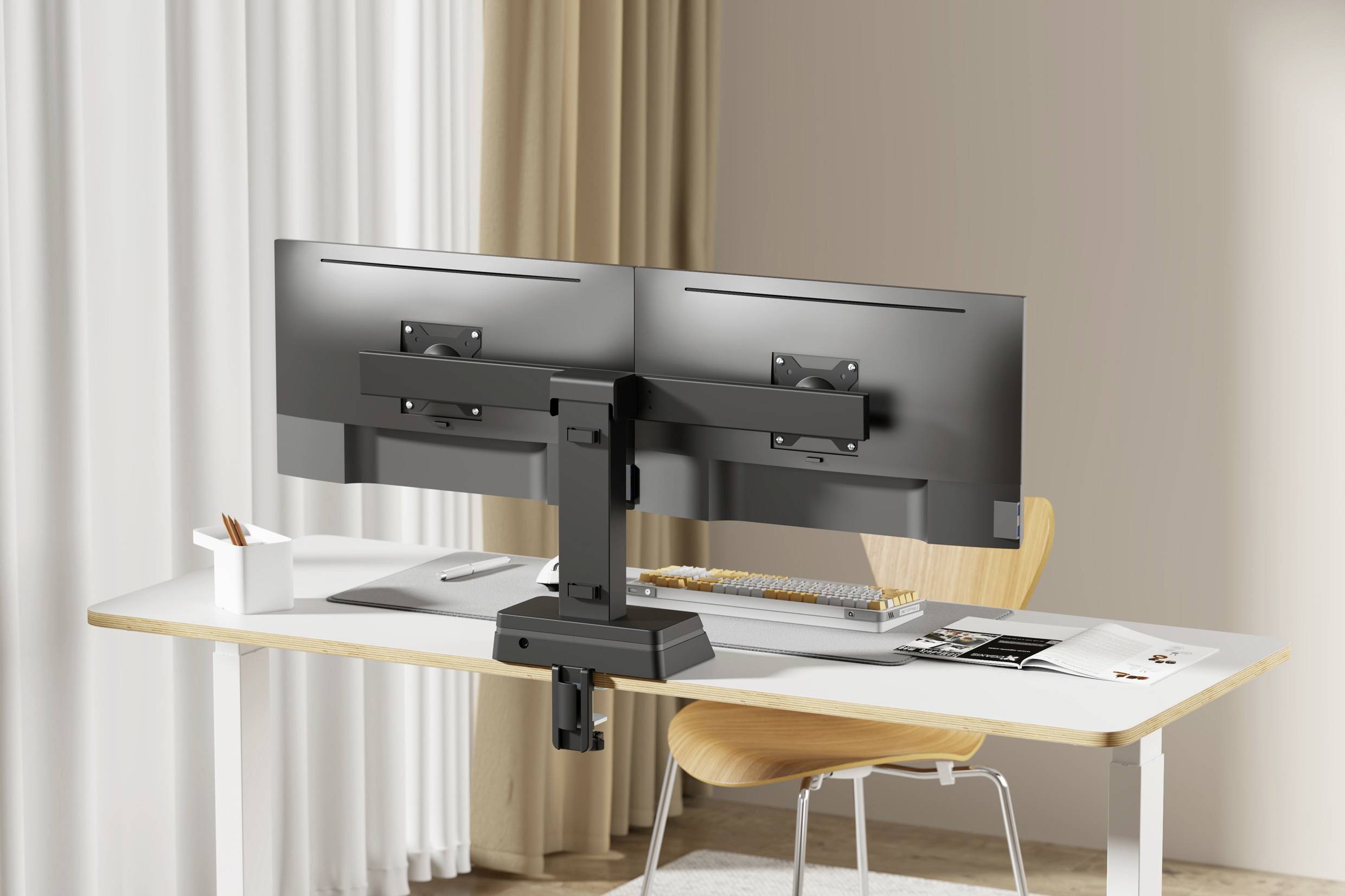 A modern home office desk setup with a dual monitor stand, wooden chair, and neatly arranged stationery. The room has light curtains and neutral colors.