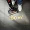 Vacuum cleaner removes crumbs from black tiled floor. Text on floor: '180 m²'. Two white shoes visible.