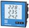 A blue Janitza energy cost analyser displays voltages on its digital display: L1 228 V, L2 235 V, L3 242 V.