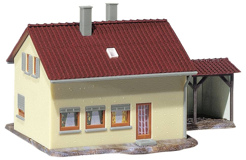 A model house with a red tiled roof, yellow walls, multiple windows, and an attached carport is depicted.