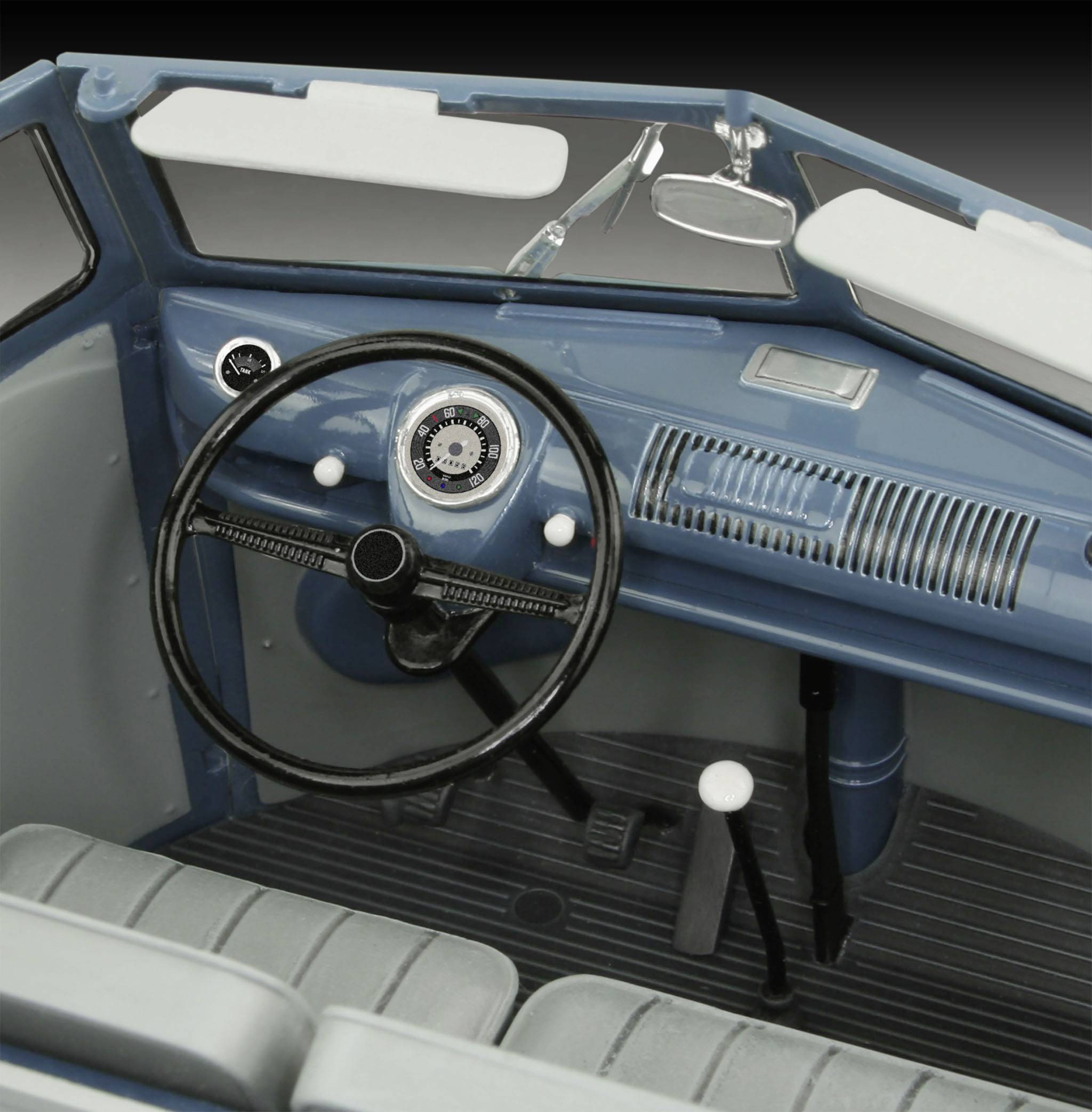 Interior of a classic car: steering wheel, vintage dashboard with speedometer, blue-grey seats, and vehicle instruments.