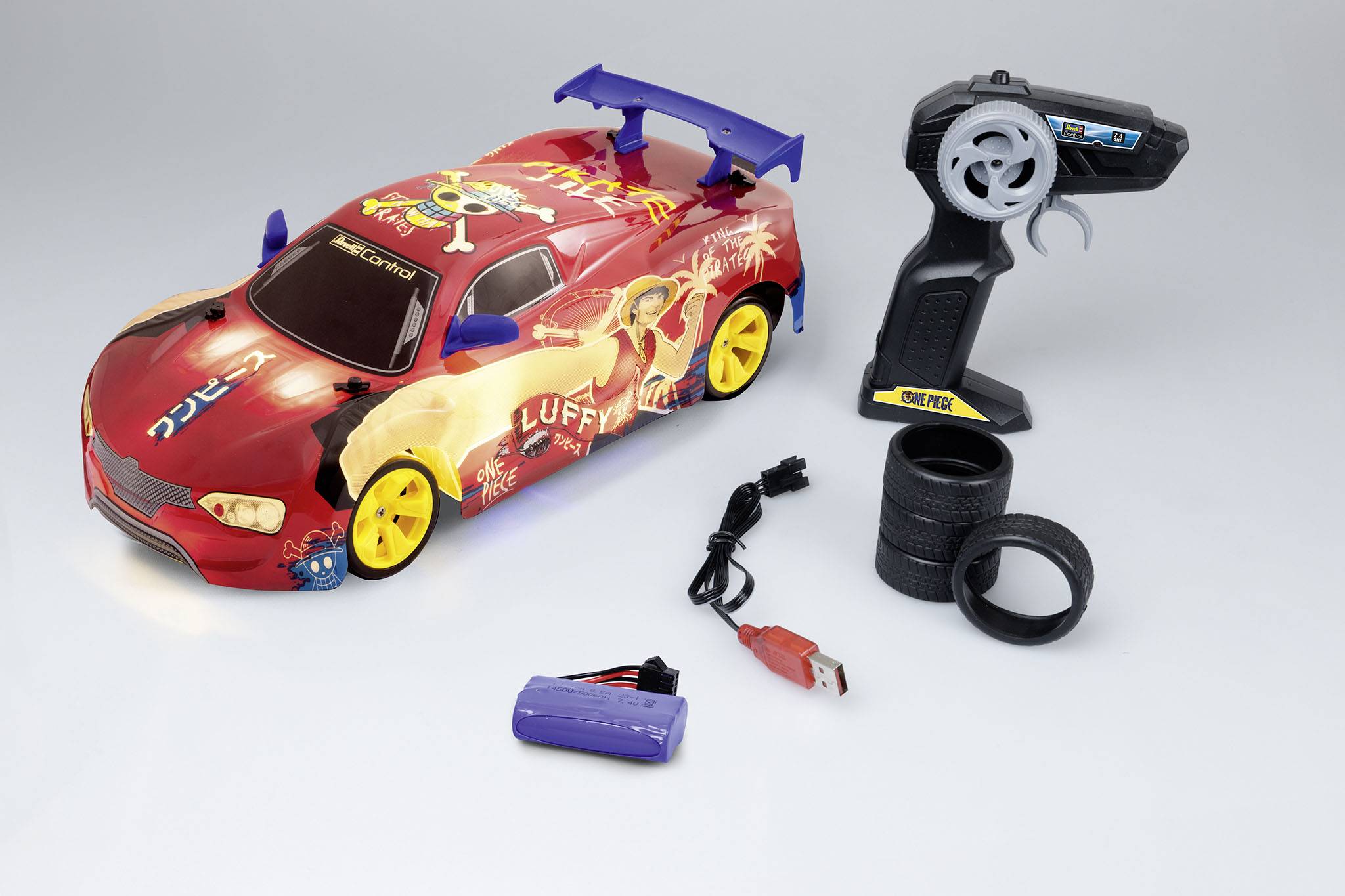 Toy racing car with colourful design, yellow wheels, remote control with steering wheel, charger, and battery on a grey background.