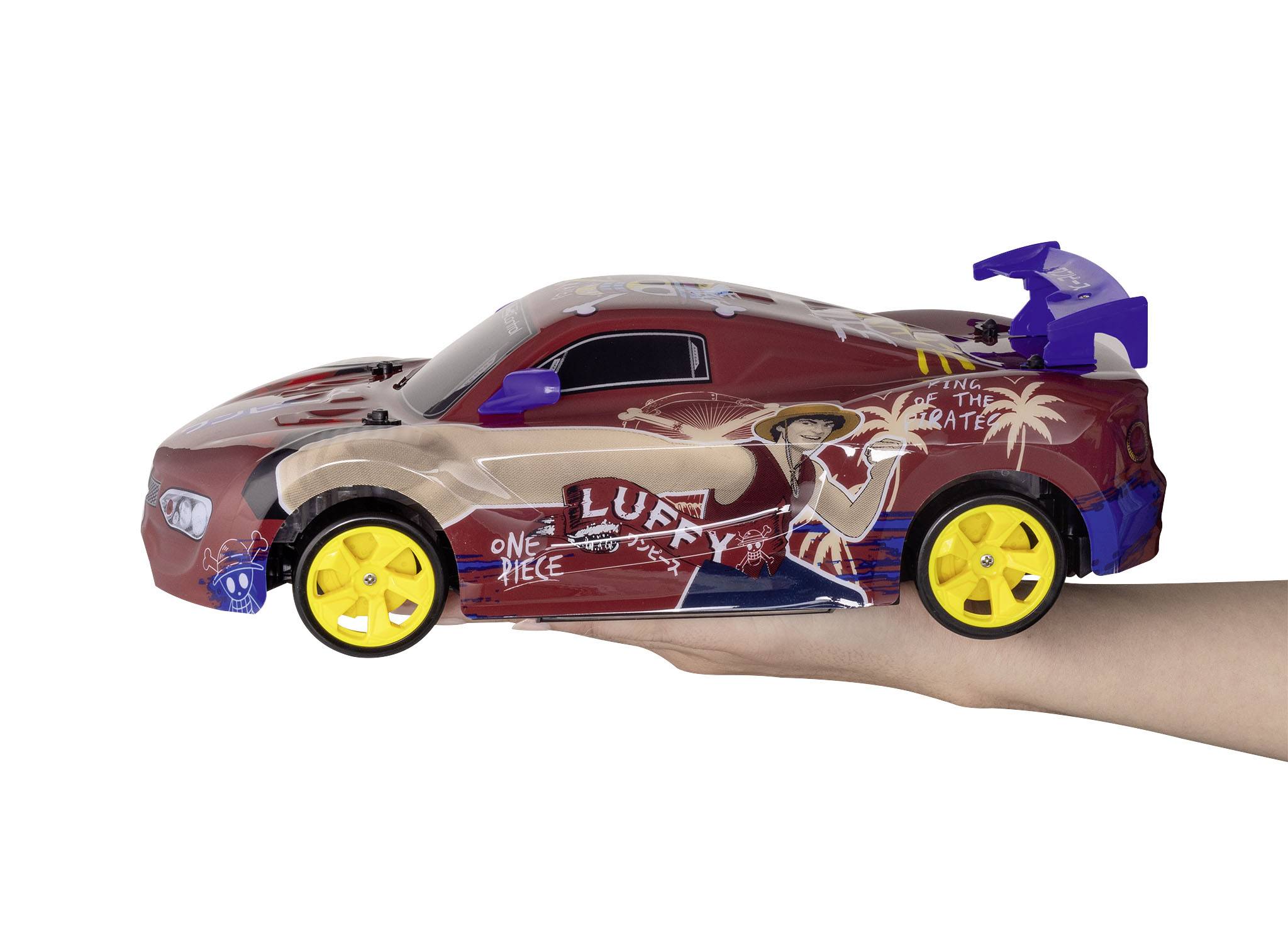 Toy car with a 'One Piece' theme held in a hand. Red car with yellow wheels and blue details, depicting manga character Luffy.