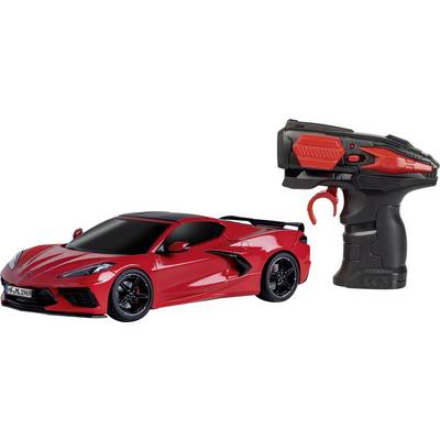 Remote-controlled car next to its matching remote control. The car is sportily designed with black wheels and smooth lines.