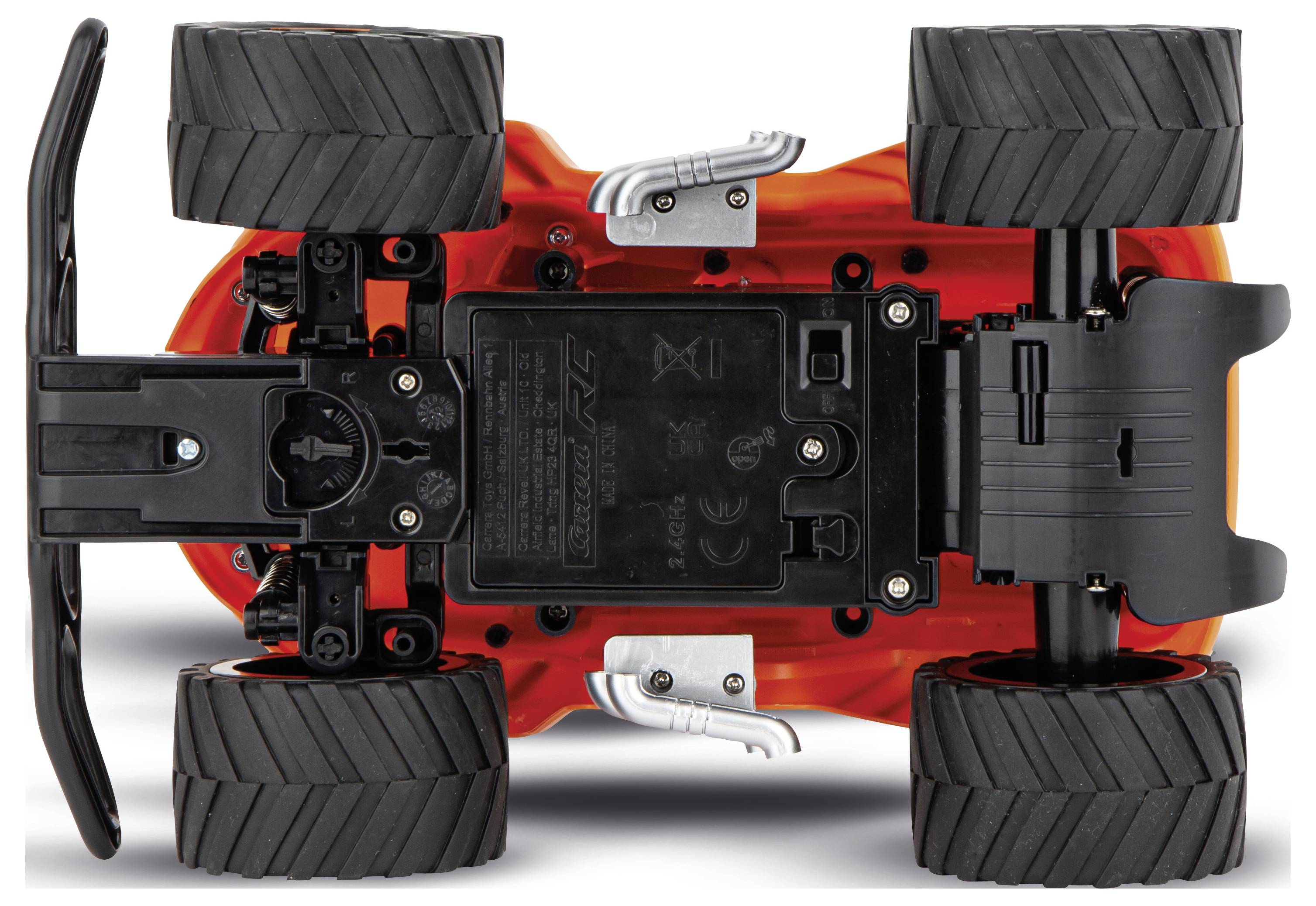 Underside of a remote-controlled car with large, black tyres. Screw holes visible; front and rear axles distinguishable.