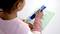 A child is using a blue pen to complete a task on a worksheet with pictures of animals and symbols.