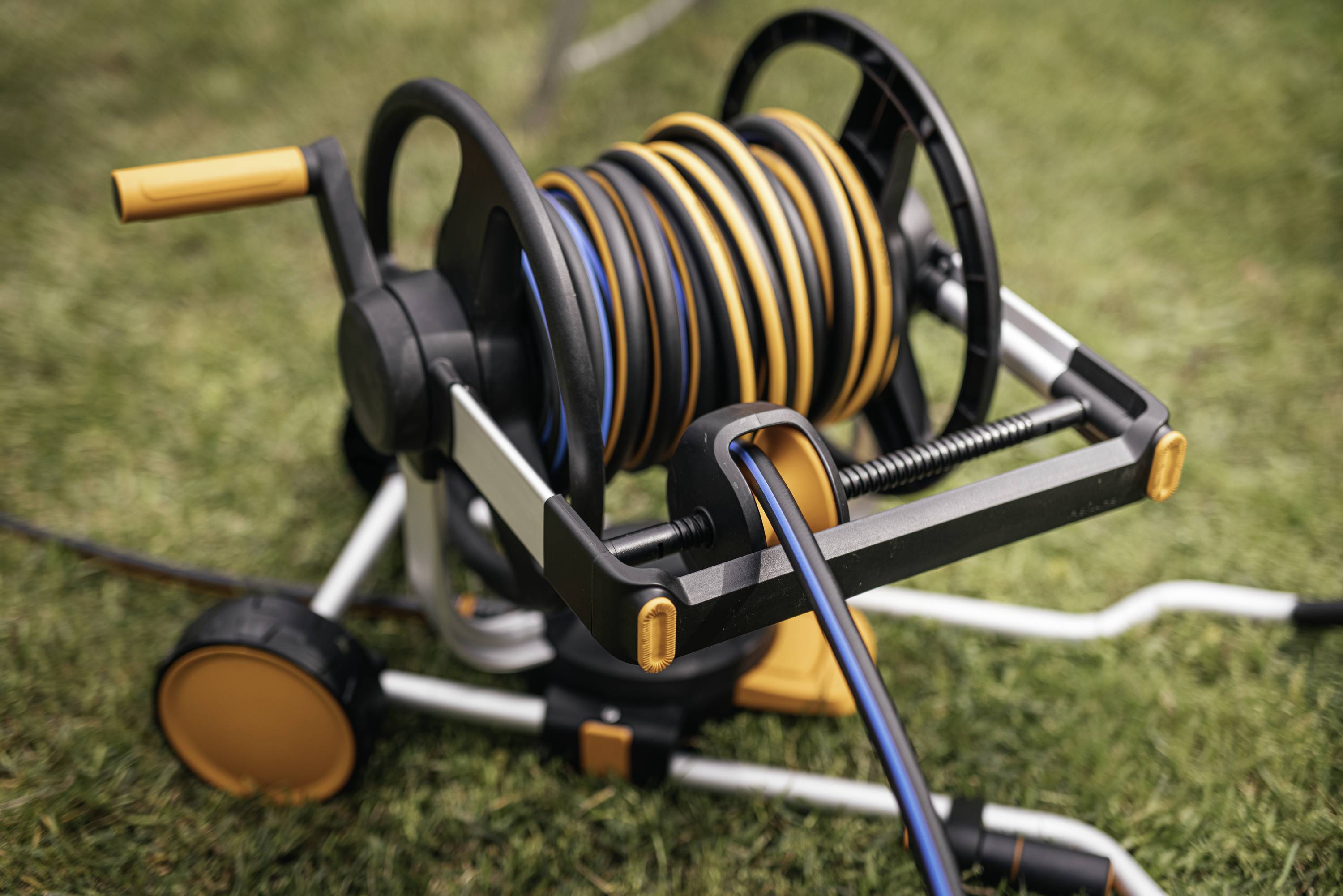 Garden hose reel with rolled-up hose on a lawn area.