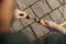 A person is connecting two parts of a garden hose with connectors on a paved surface.