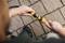A person connects garden hoses with yellow couplings on a paved path. The focus is on the hands and the connection.