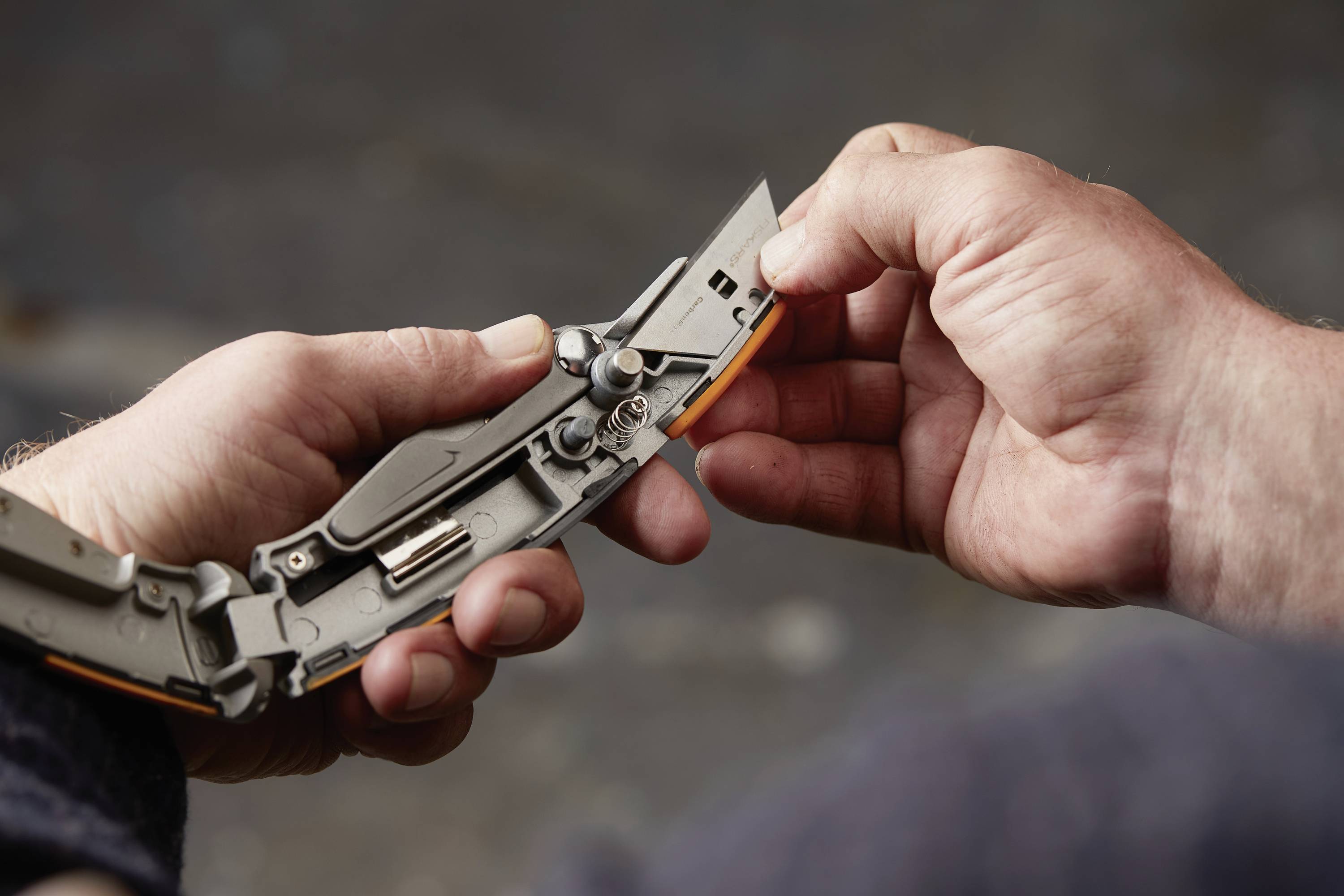 A person is holding an open penknife in their hand and examining its mechanism.