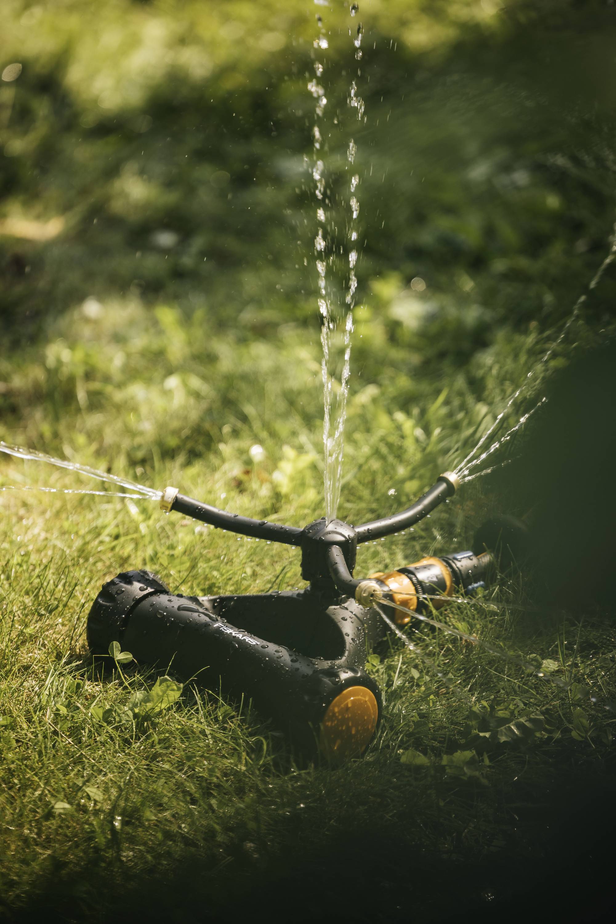 'A lawn sprinkler is spraying water onto a green lawn to irrigate the grass.'