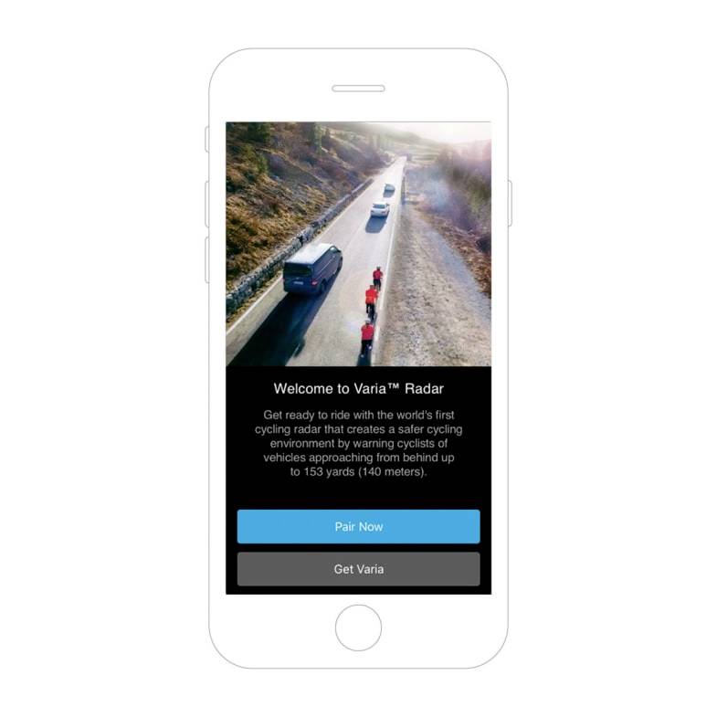 A cyclist is riding on a road, followed by a car. A warning system informs about vehicles approaching from behind.