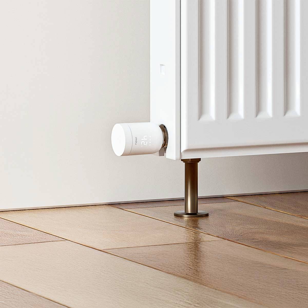 'Close-up of a white radiator with a digital thermostat displaying the temperature at 21 degrees Celsius. Parquet flooring.'