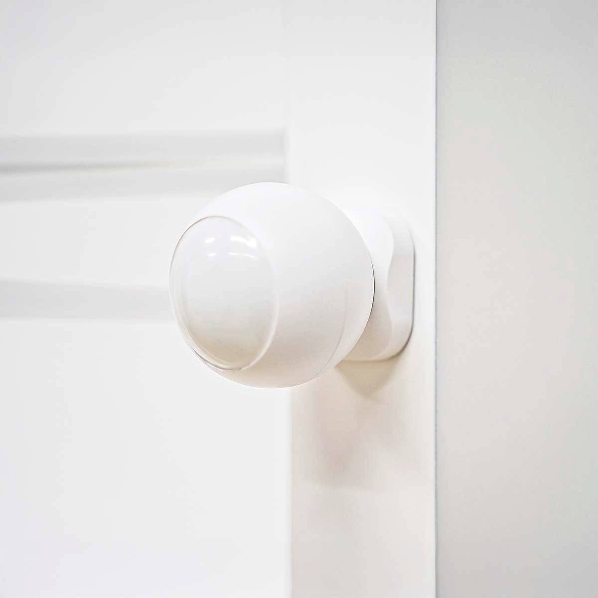 A white, spherical motion sensor mounted on a wall, ready to detect movement for automation or security purposes.