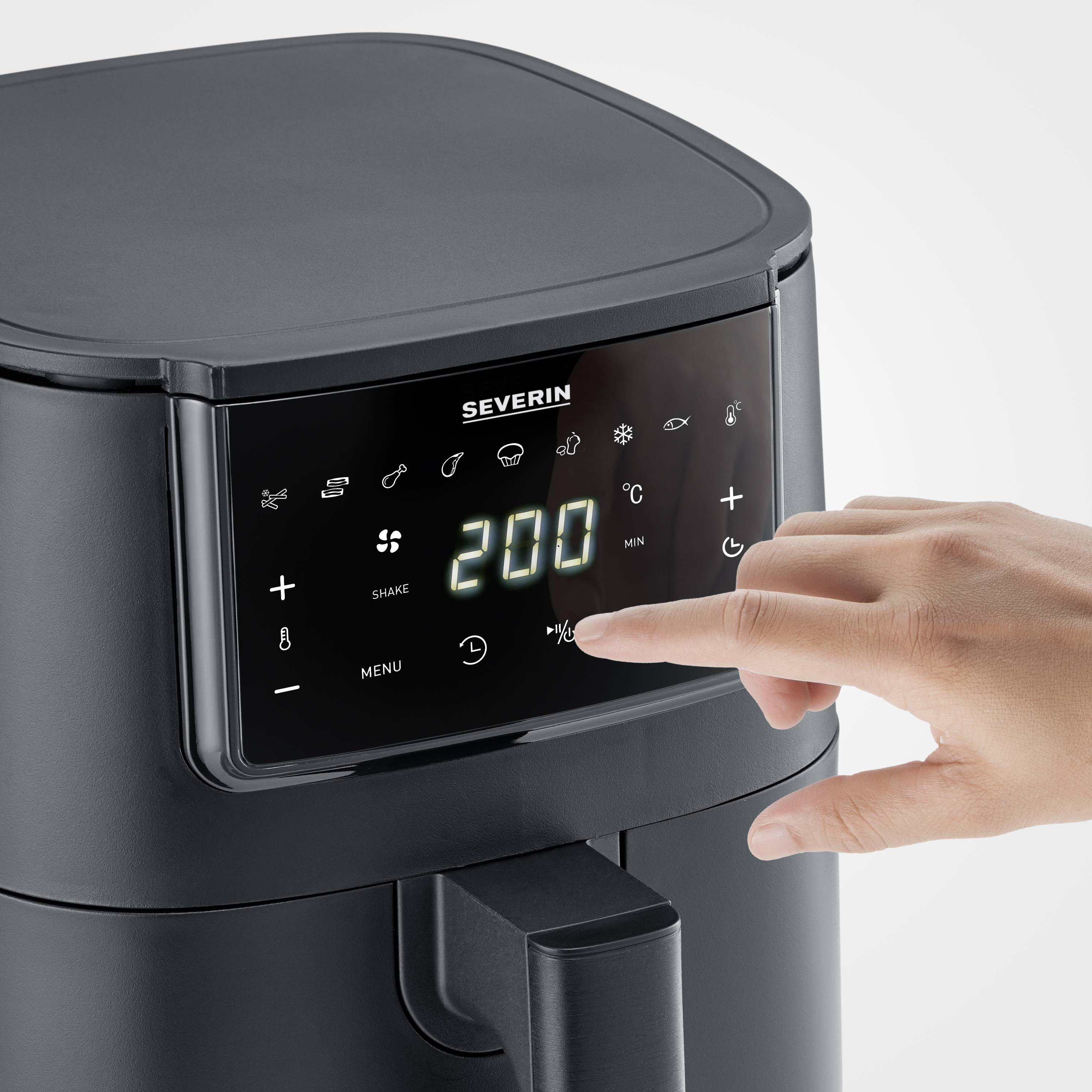 A hand is tapping the control panel of a black air fryer to set the temperature to 200 degrees.