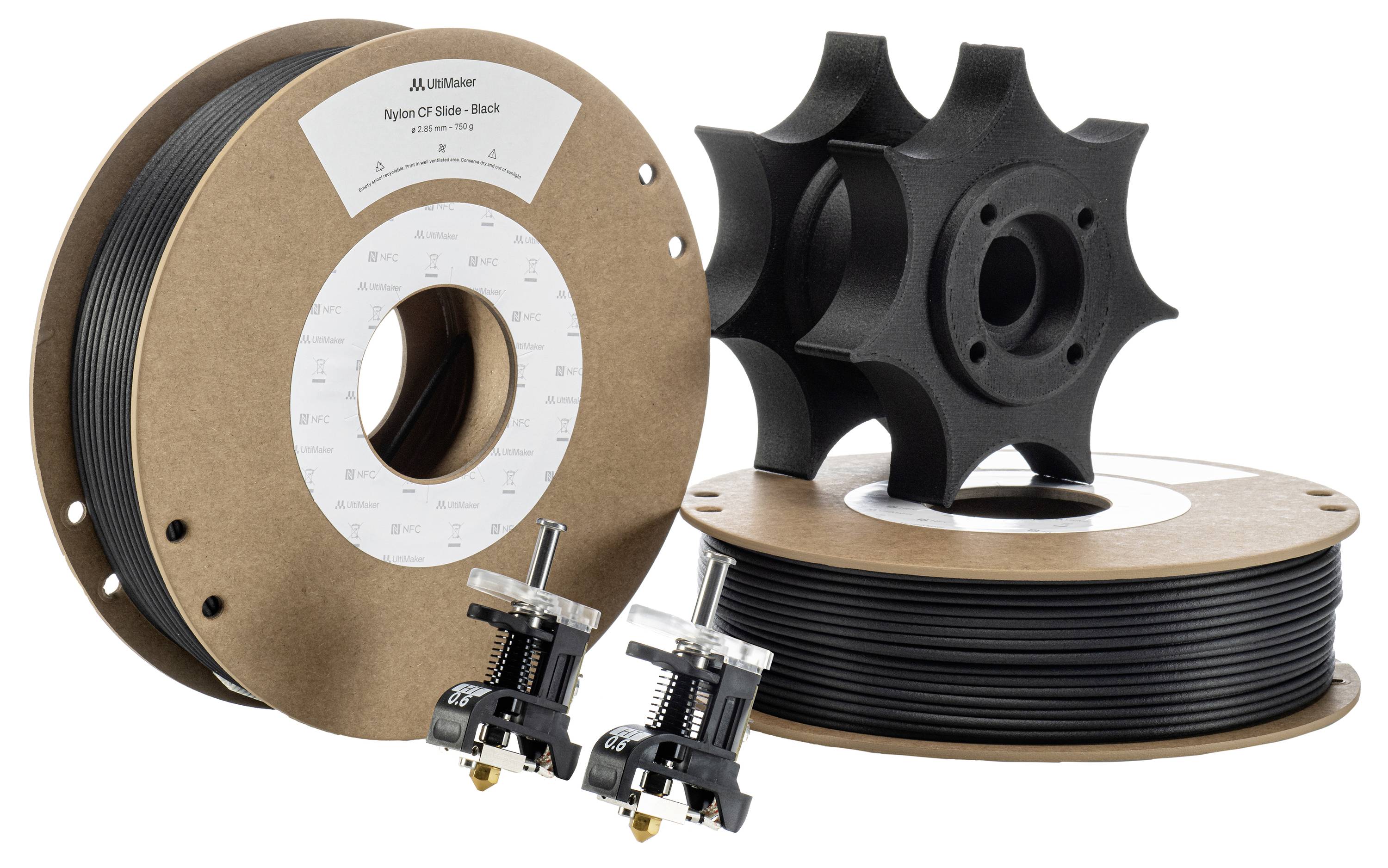 3D printing filament on spools, black in colour. Beside them lie two 3D-printed gears and two nozzle attachments for use.