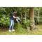A person is emptying a container of garden waste onto a compost heap in the woods. Surrounded by trees and lush greenery.