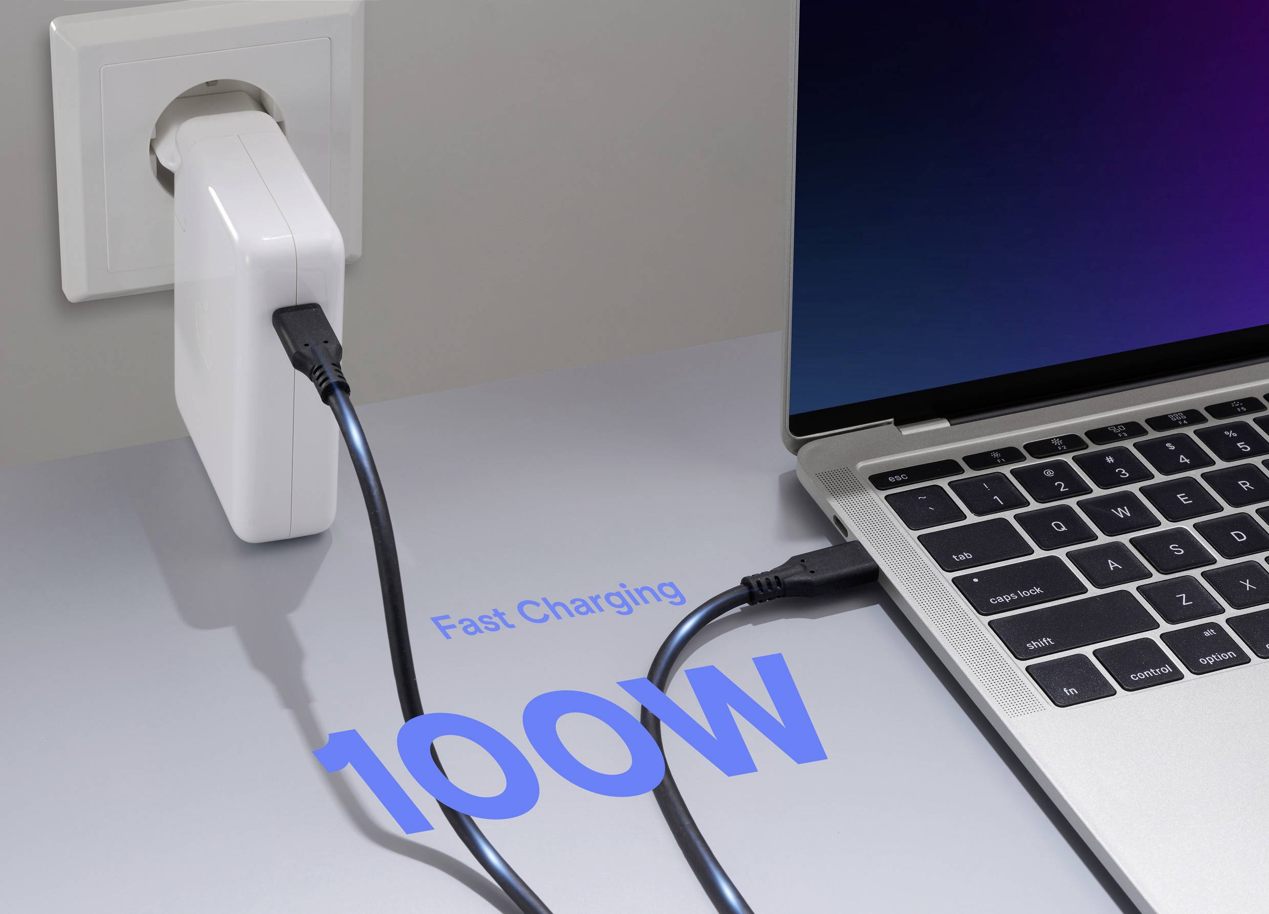 A laptop is connected to a wall charger labeled '100W Fast Charging', illustrating high-speed battery charging capability.