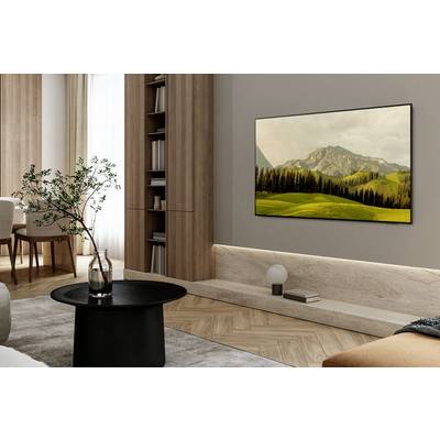 Living room with modern furnishings, a central black table, a decorative tree branch, and a landscape painting on the wall.