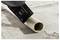 A saw blade is cutting through a plastic pipe on a concrete surface, creating a clean cut.