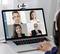 A person participates in a video conference on a laptop with four diverse business professionals, each in individual video frames.