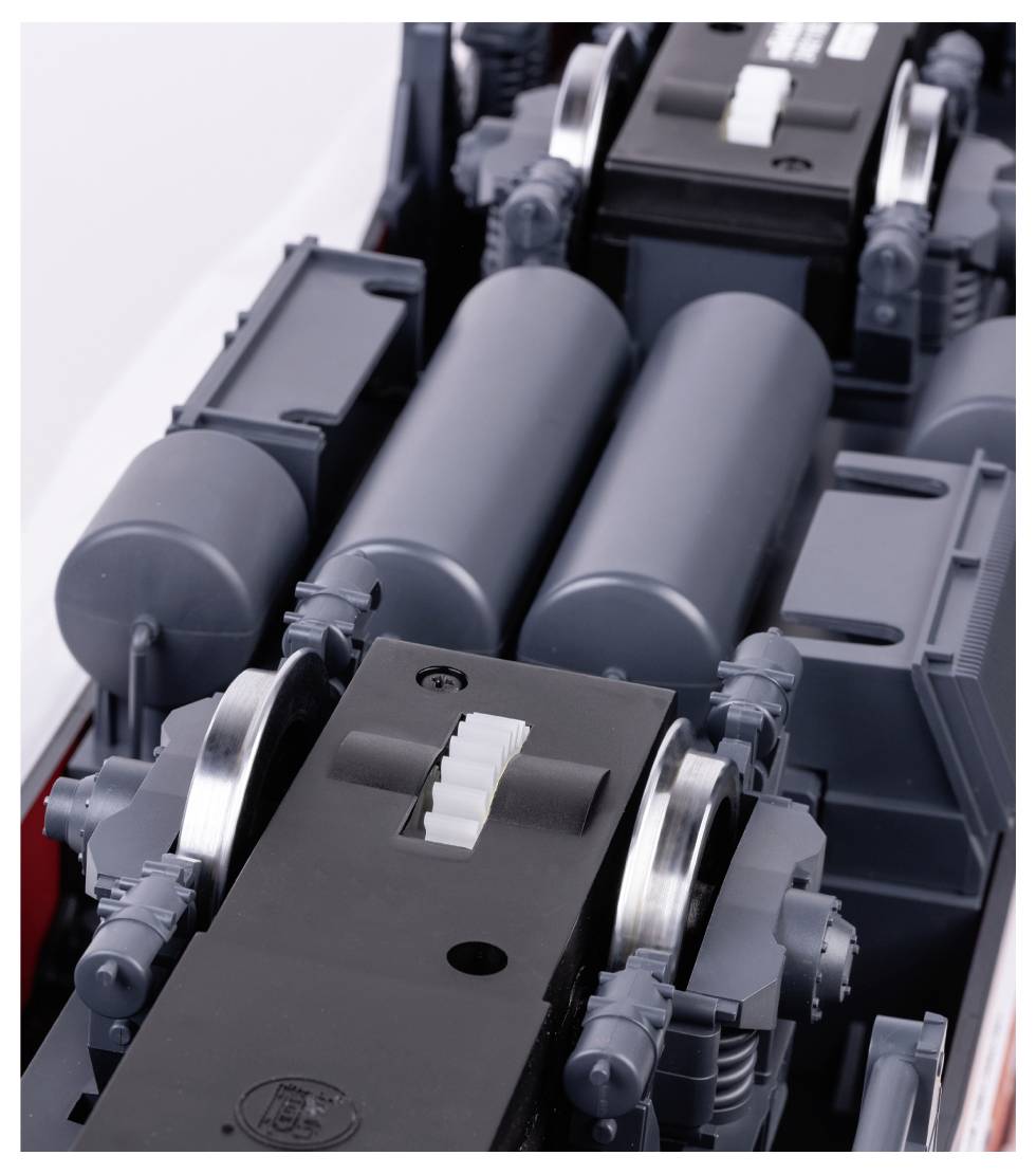 Close-up of parts of a grey, industrially manufactured machine with metal rollers and multiple cylinders. Function unknown.