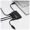 USB hub with four ports, connected to a laptop. Three cables are plugged in. The hub is black and rectangular.