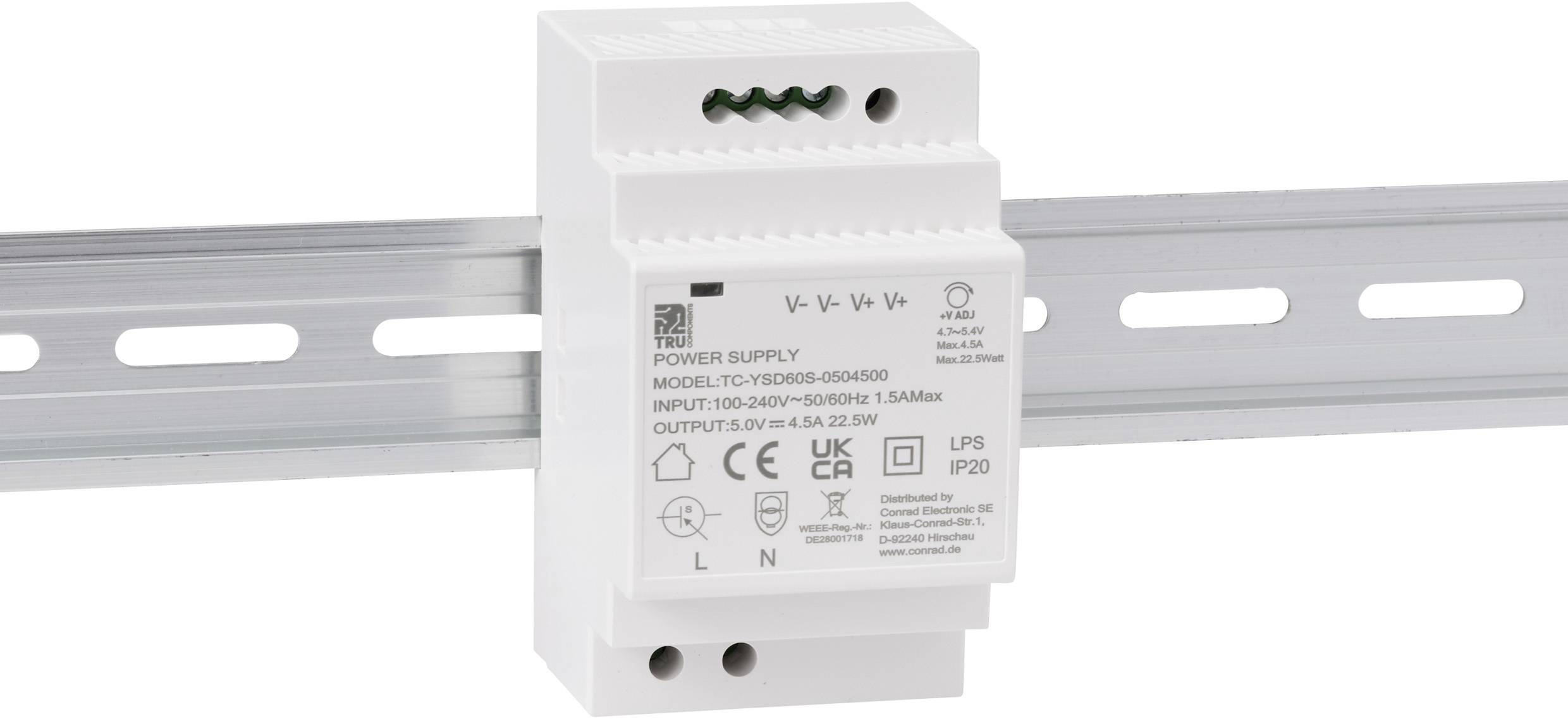 A white power supply device mounted on a metal DIN rail, labeled with technical specifications and safety certification symbols.