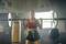 Woman in sportswear lifting a barbell in a gym. A punching bag can be seen in the background.