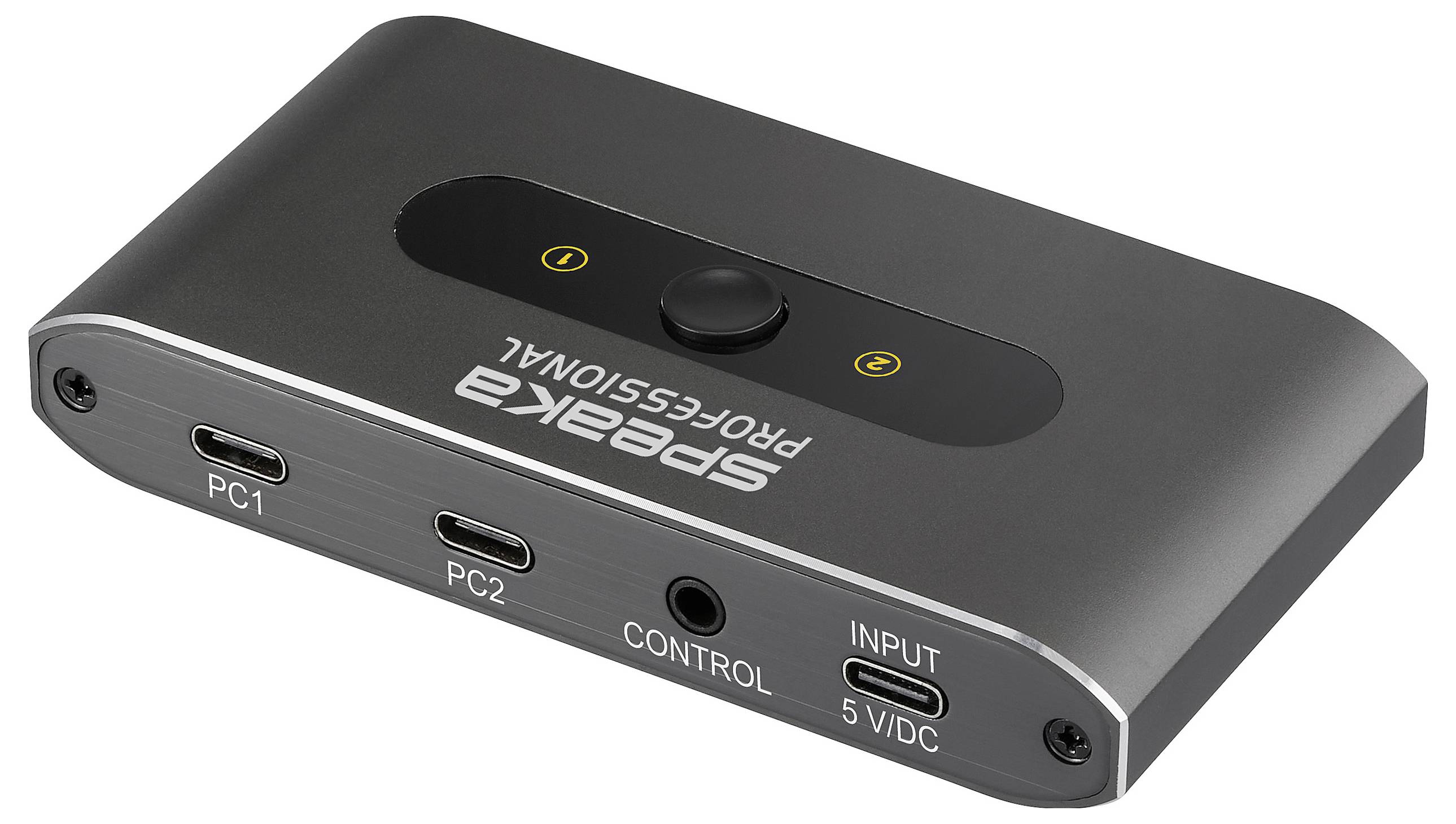 A black Speaka Professional USB switch with ports labeled 'PC1', 'PC2', 'CONTROL', and 'INPUT 5V/DC', used for connecting devices.