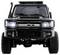 Front view of a black SUV with a bulky grille and headlights on, on unpaved terrain.