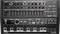 Analog synthesizer with multiple rotary knobs and sliders, a display, and a sequencer section with pads and control buttons.