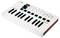 A white MIDI keyboard with 25 keys, eight illuminated drum pads and rotary controls. It is placed on a table.