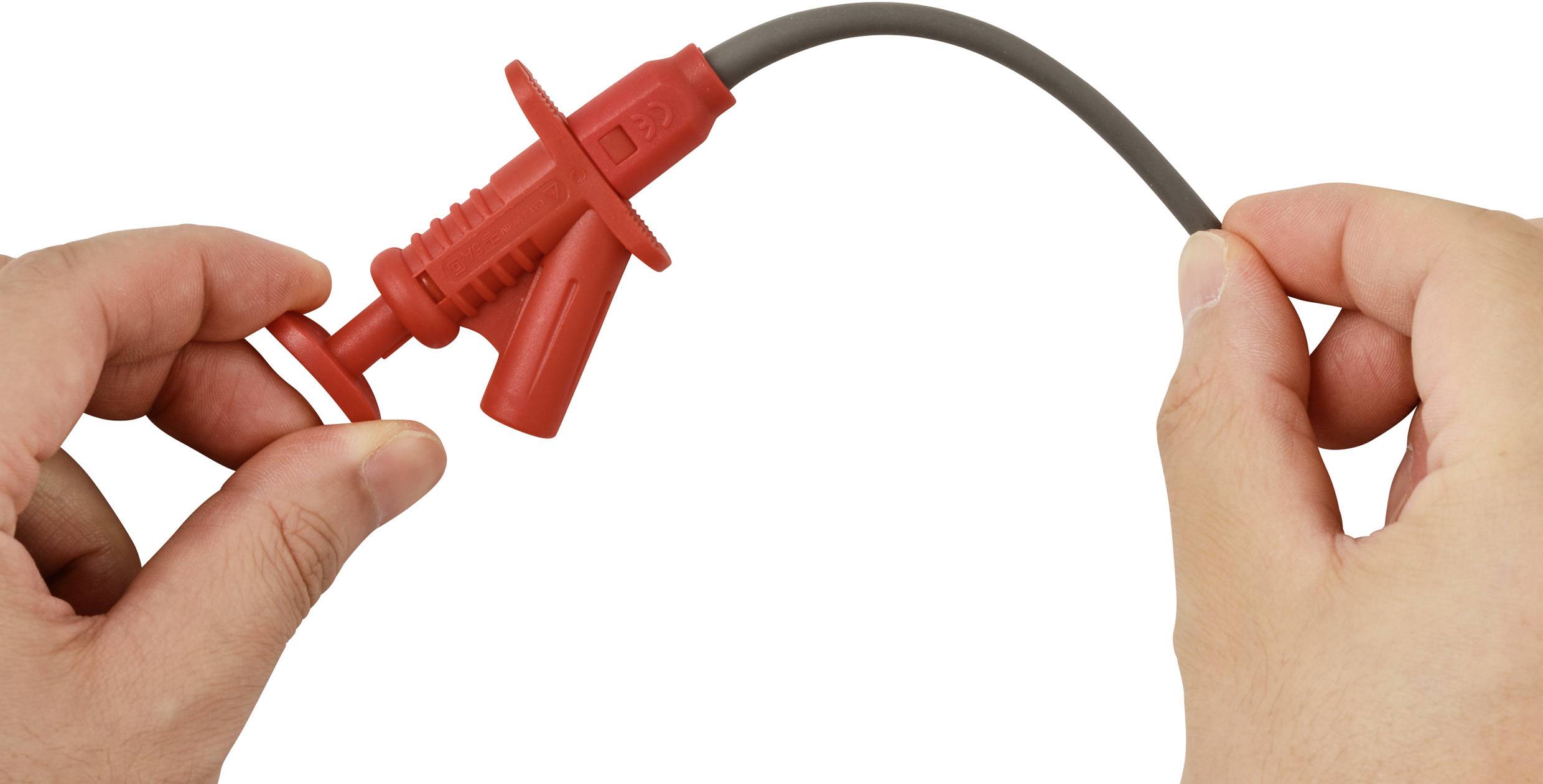 A person holds a red test lead with hands, preparing to connect it to an electronic device for testing or measurement.