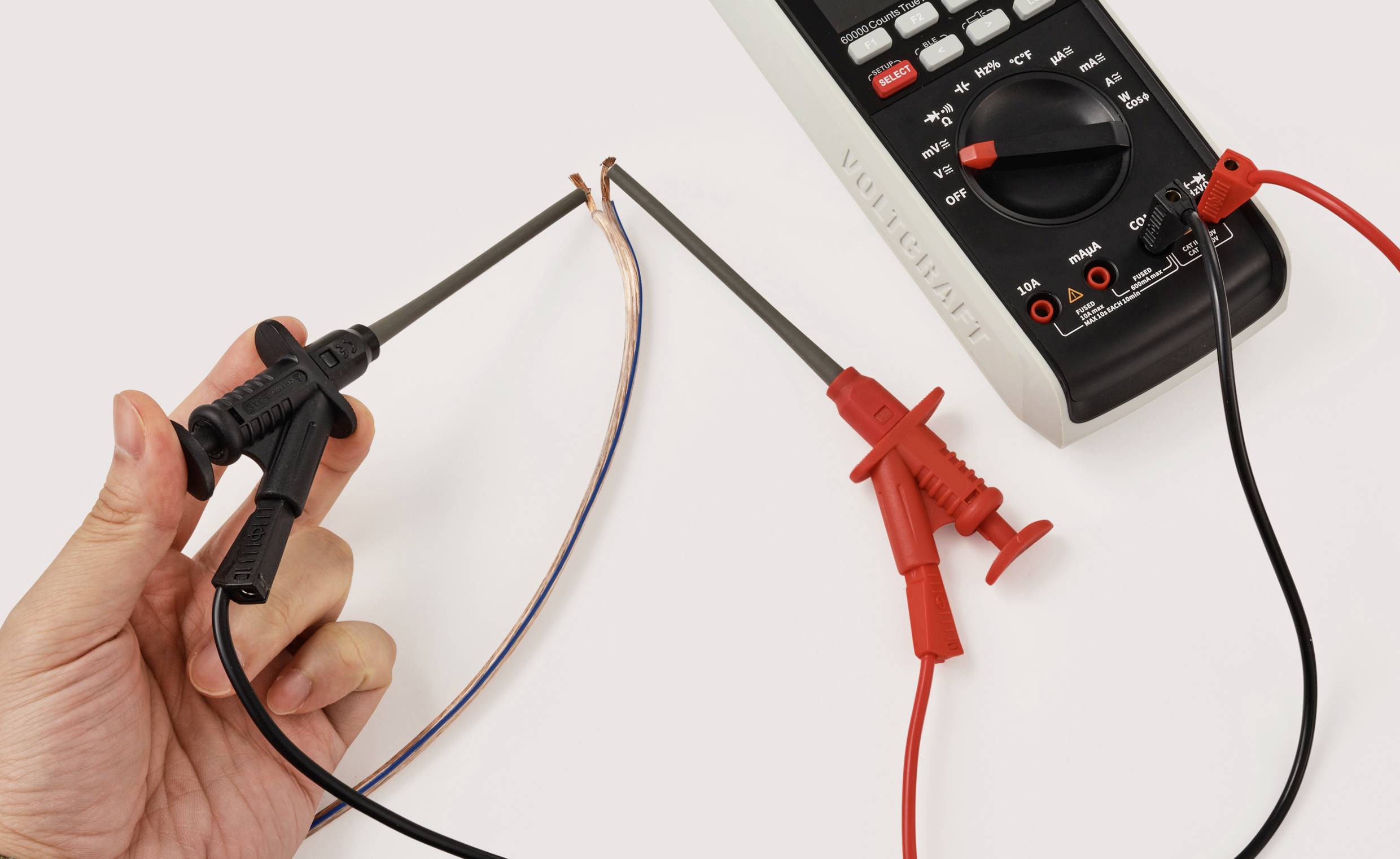 A hand uses a multimeter to measure voltage across two exposed wires, showcasing electrical testing or troubleshooting.