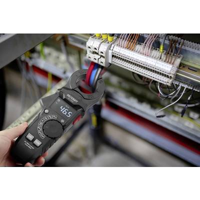 'A person uses a digital clamp meter to measure electrical current in a circuit with multiple wires, displaying a reading of 46.5.'