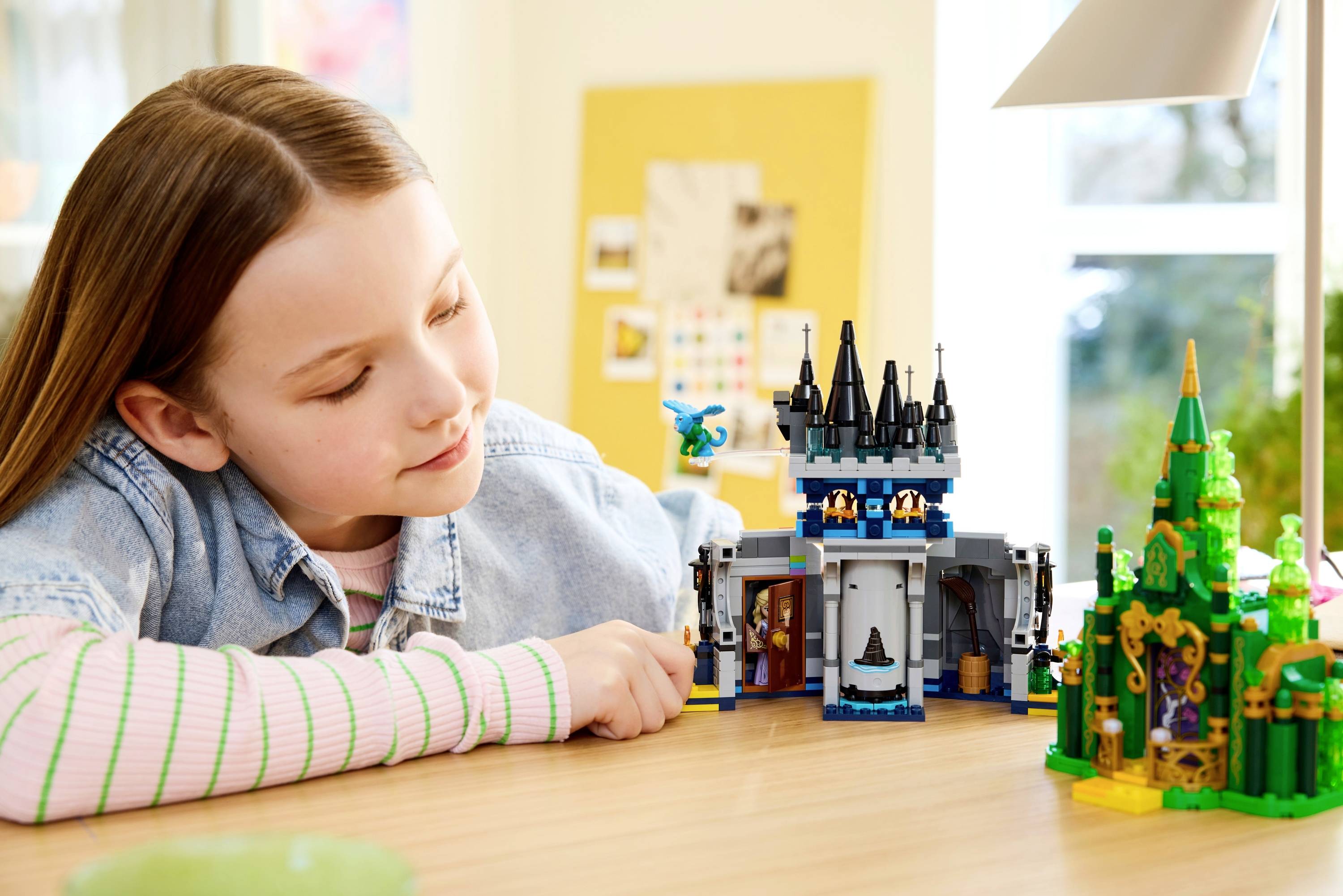 A child plays with colorful building block castles on a table, appearing focused and imaginative.