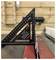 A black carpenter's square with silver markings is positioned on a workbench, with wooden panels in the background.