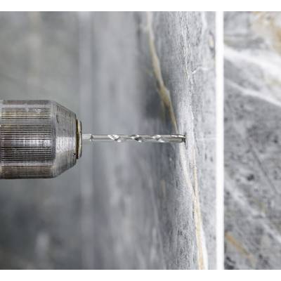 'A drill is making a hole in a concrete wall.'