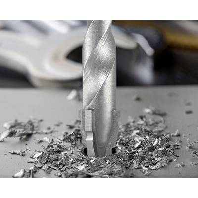 A close-up of a metal drill bit actively drilling into a grey surface, surrounded by scattered metal shavings.