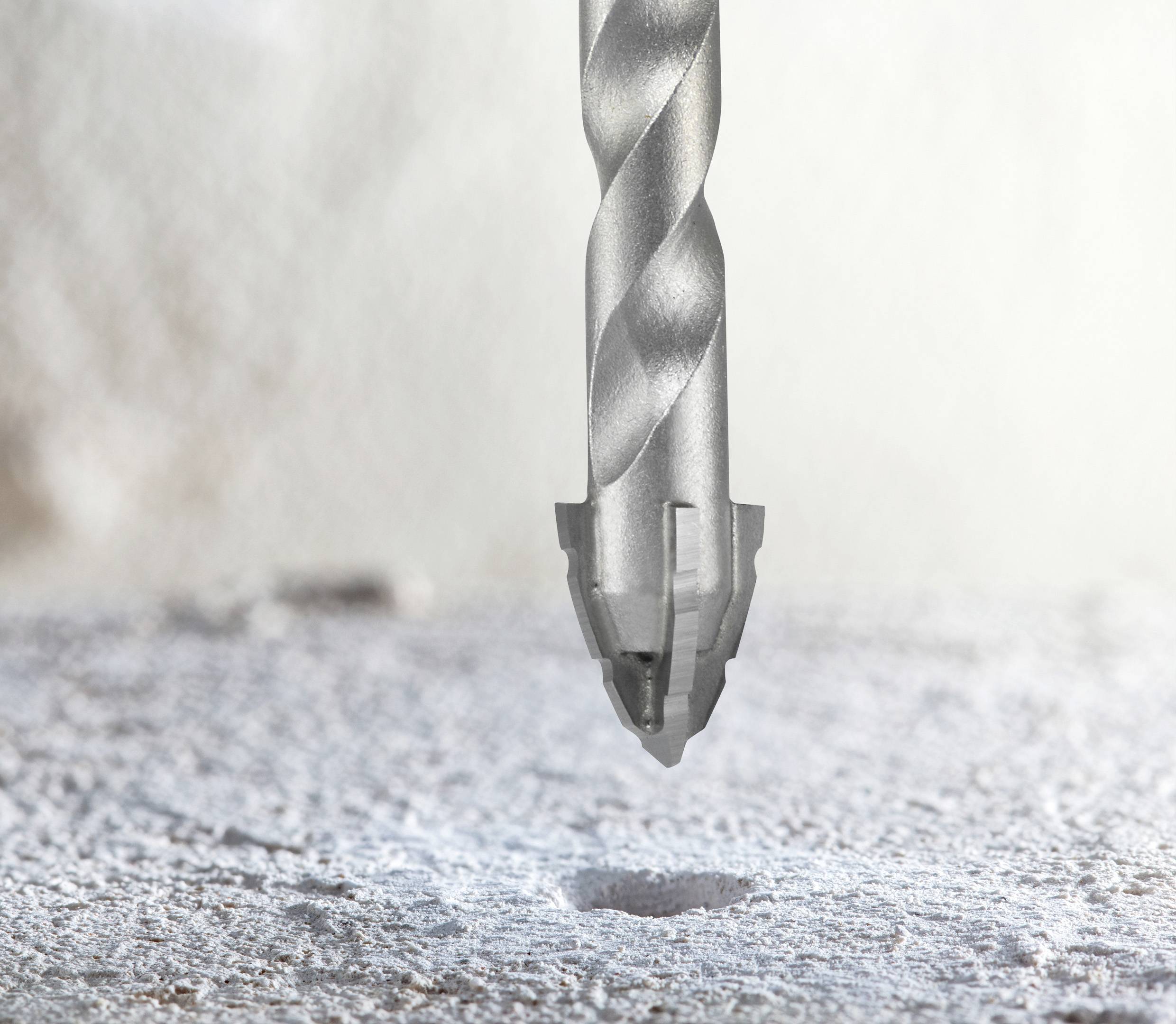 A drill bit poised above a concrete surface, highlighting precision in drilling tasks.