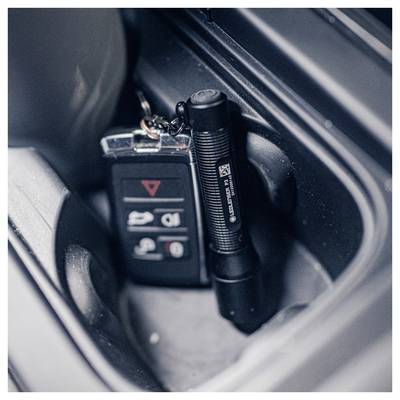 Close-up of a car's center console showing a key fob and a small flashlight tucked into a storage compartment.