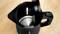 A black electric kettle with the lid open, showing a shiny stainless steel interior, sits on a wooden surface.