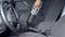 A person uses a handheld vacuum to clean the interior of a car, focusing on the area between the driver and passenger seats.